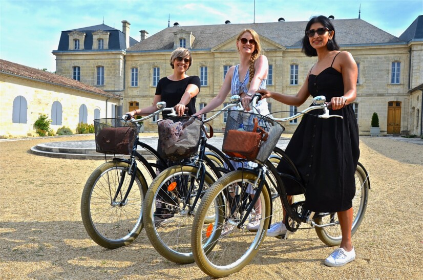 A group of friends pose for a photo on their bikes in front of Chateau Soutard