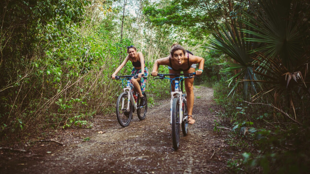 Two women ride bikes through the jungle in Tulum, Mexico