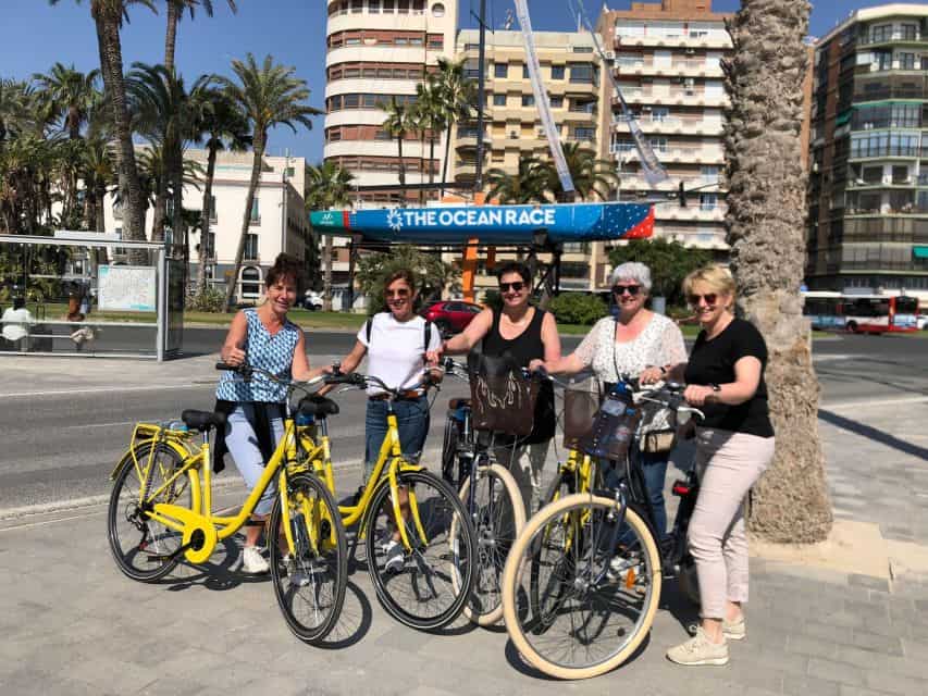 A group of cyclists pose for a photo with their bikes in front of an Ocean Race sign