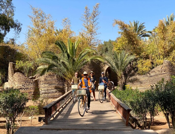 A group of cyclists ride across a bridge in a green area of Agadir-