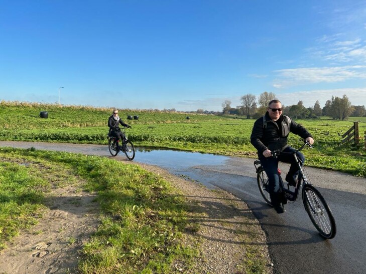 2 people bike along a path outside Amsterdam