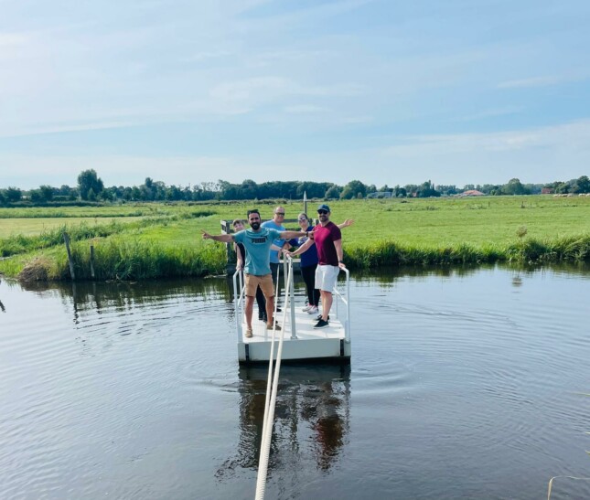 A group of people standing on a small pontoon on a lake outside Amsterdam