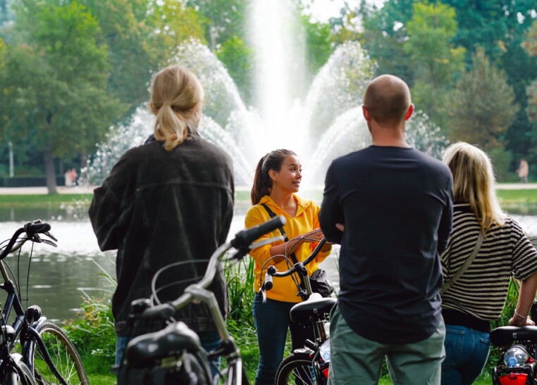 A tour guide stops to explain the surroundings in Amsterdam in front of a fountain