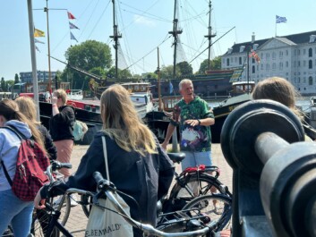 A tour guide stops to explain the surroundings to a group of cyclists along a canal in Amsterdam