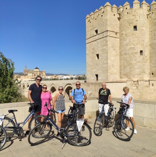 A group of cyclists who stopped for a photo in front of the Roman Bridge in Córdoba